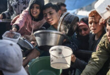 Niños y jóvenes se esfuerzan por alcanzar una porción de la comida que llega con la ayuda humanitaria a la Franja de Gaza.