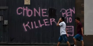 Unos hombres pasan junto a un grafiti con el nombre de una de las bandas criminales que operan en Durán, Ecuador.