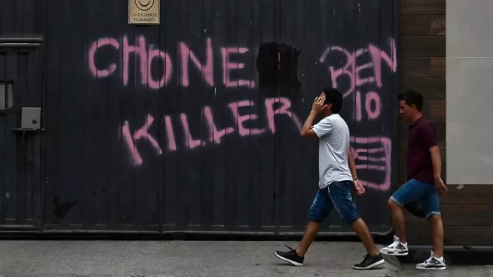 violencia ecuador Unos hombres pasan junto a un grafiti con el nombre de una de las bandas criminales que operan en Durán, Ecuador.